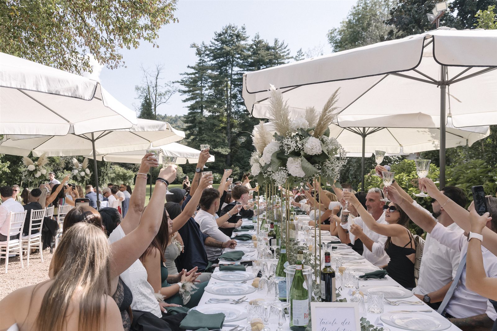 Gli invitati a tavola in giardino sotto gli ombrelloni Gli invitati a tavola in giardino sotto gli ombrelloni