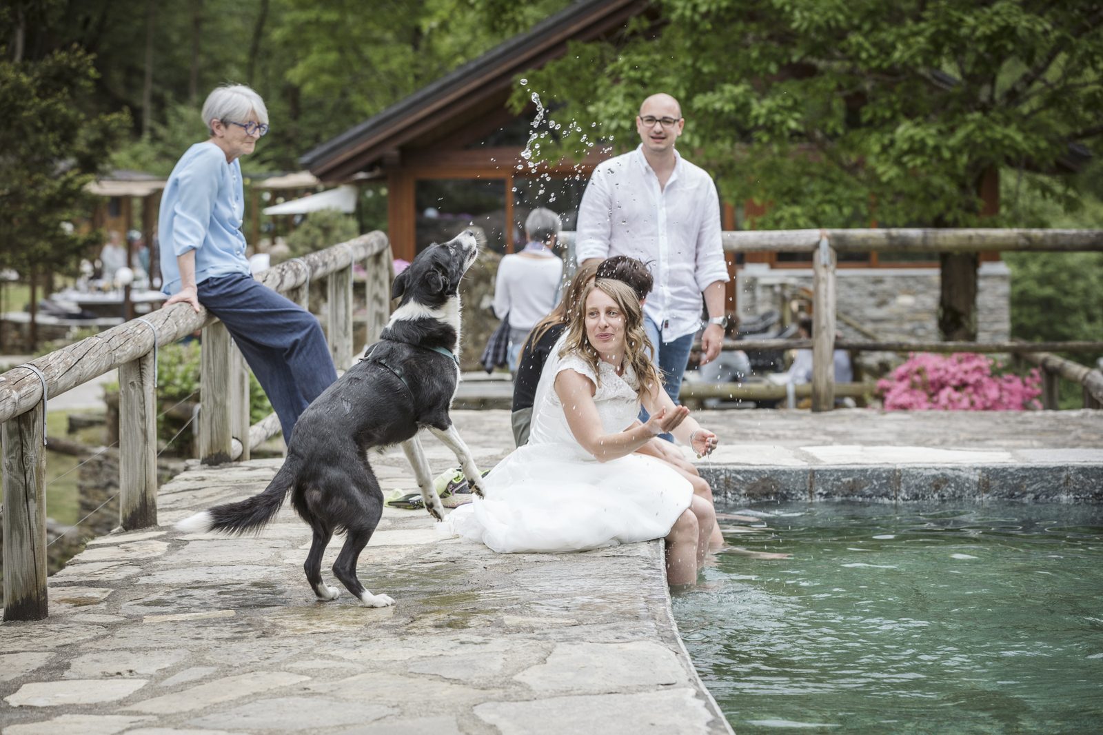 The newlyweds sitting at the edge of the natural pool with the dog