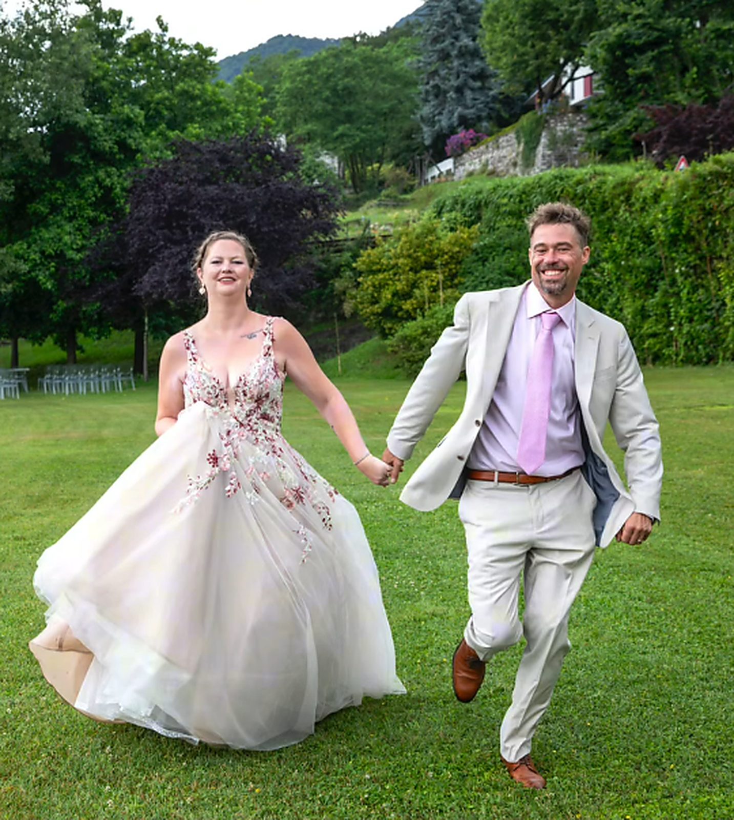 The newlyweds running hand in hand across the lawn