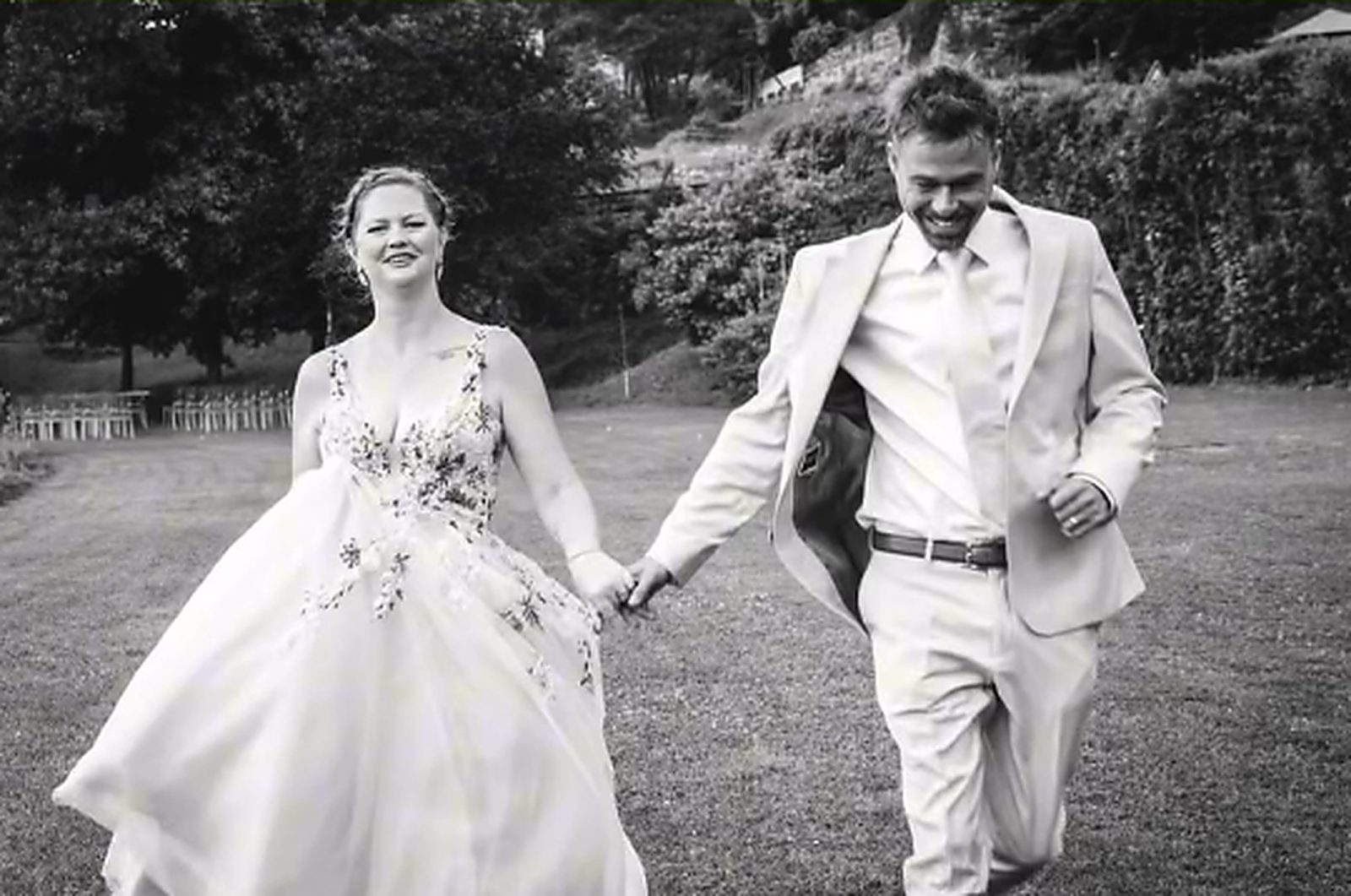 The newlyweds on the lawn, hand in hand, black and white