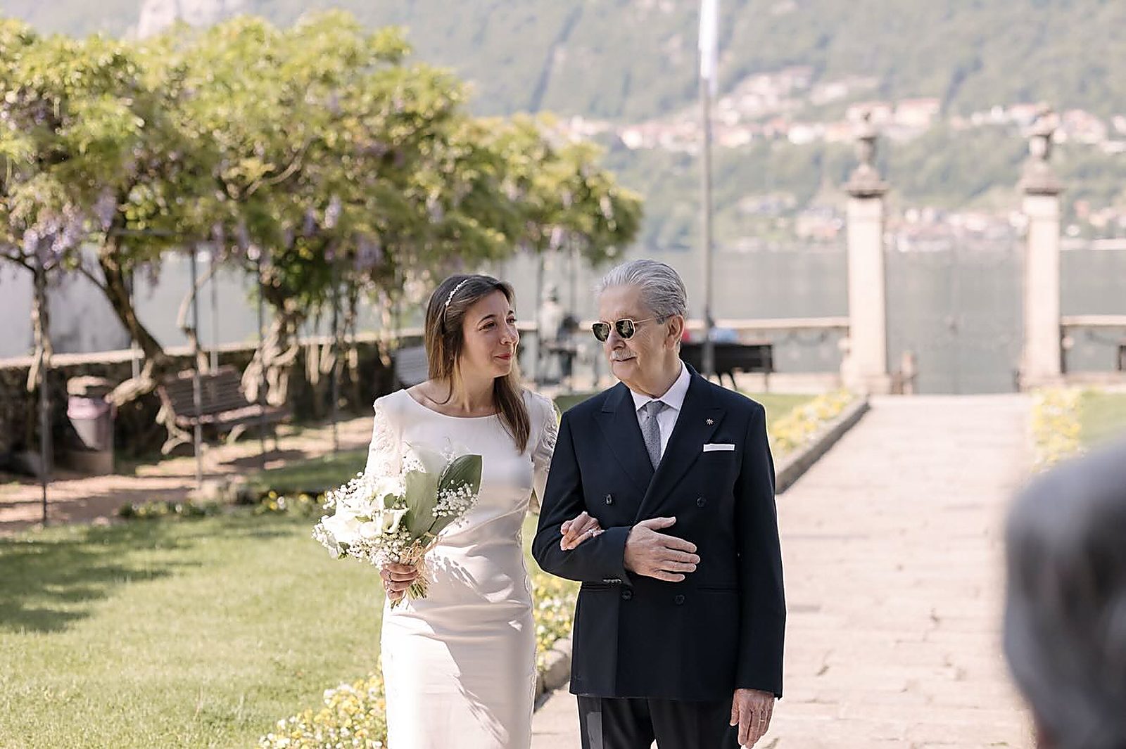 La sposa arriva a braccetto con il padre, sotto il glicine La sposa arriva a braccetto con il padre, sotto il glicine