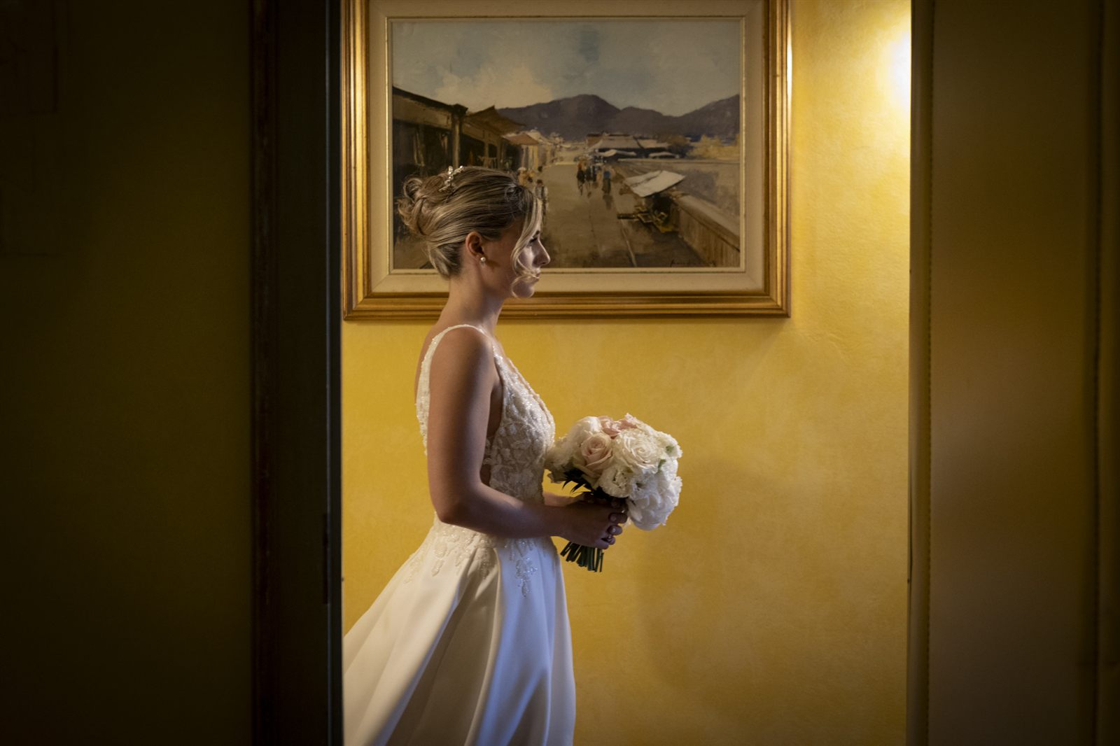 La sposa con il bouquet accanto a un quadro con vista sulle colline