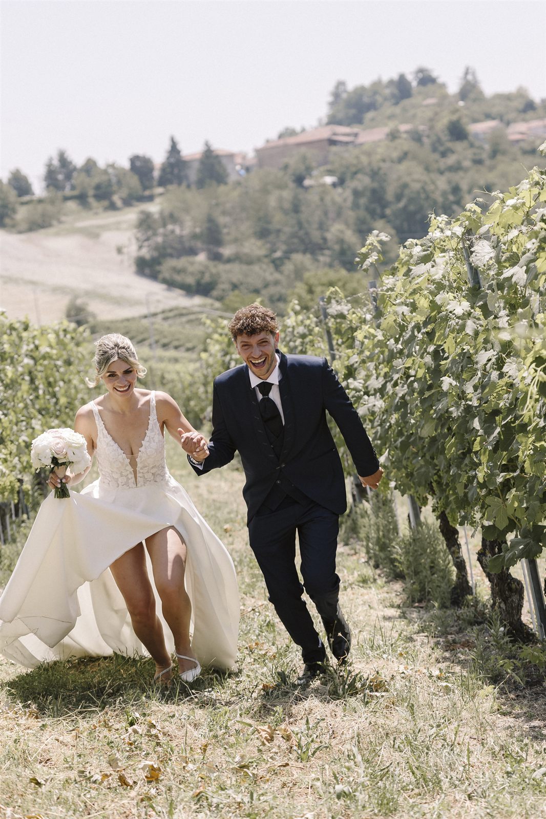 The newlyweds walking between the vineyard rows