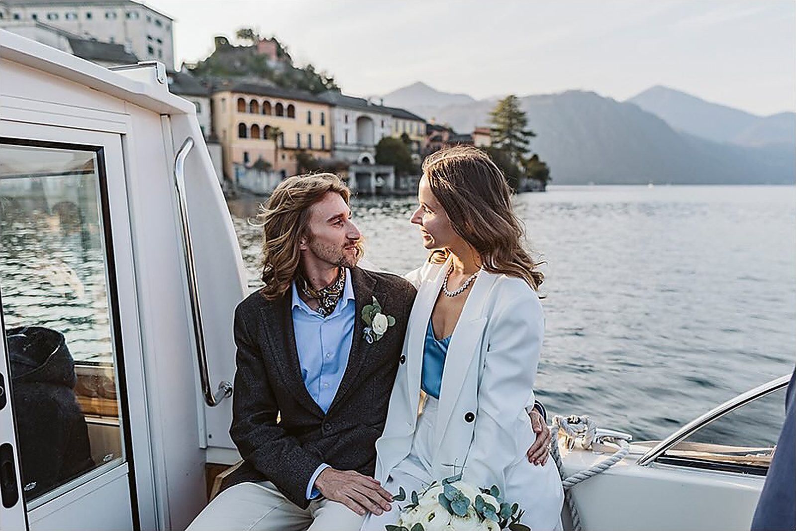 Gli sposi si guardano a bordo, il borgo di Orta alle spalle
