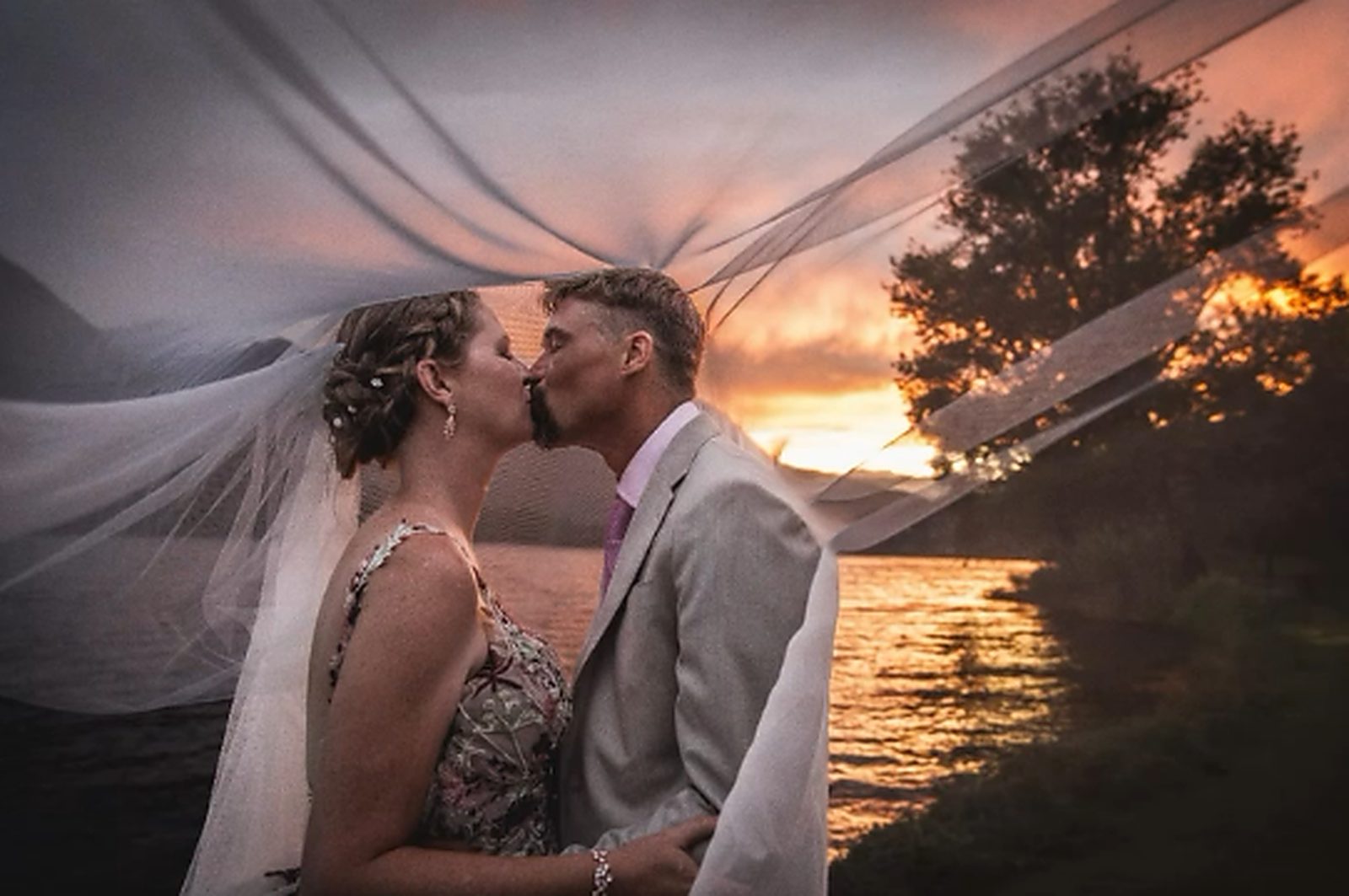 Il bacio degli sposi sotto il velo, al tramonto sul lago
