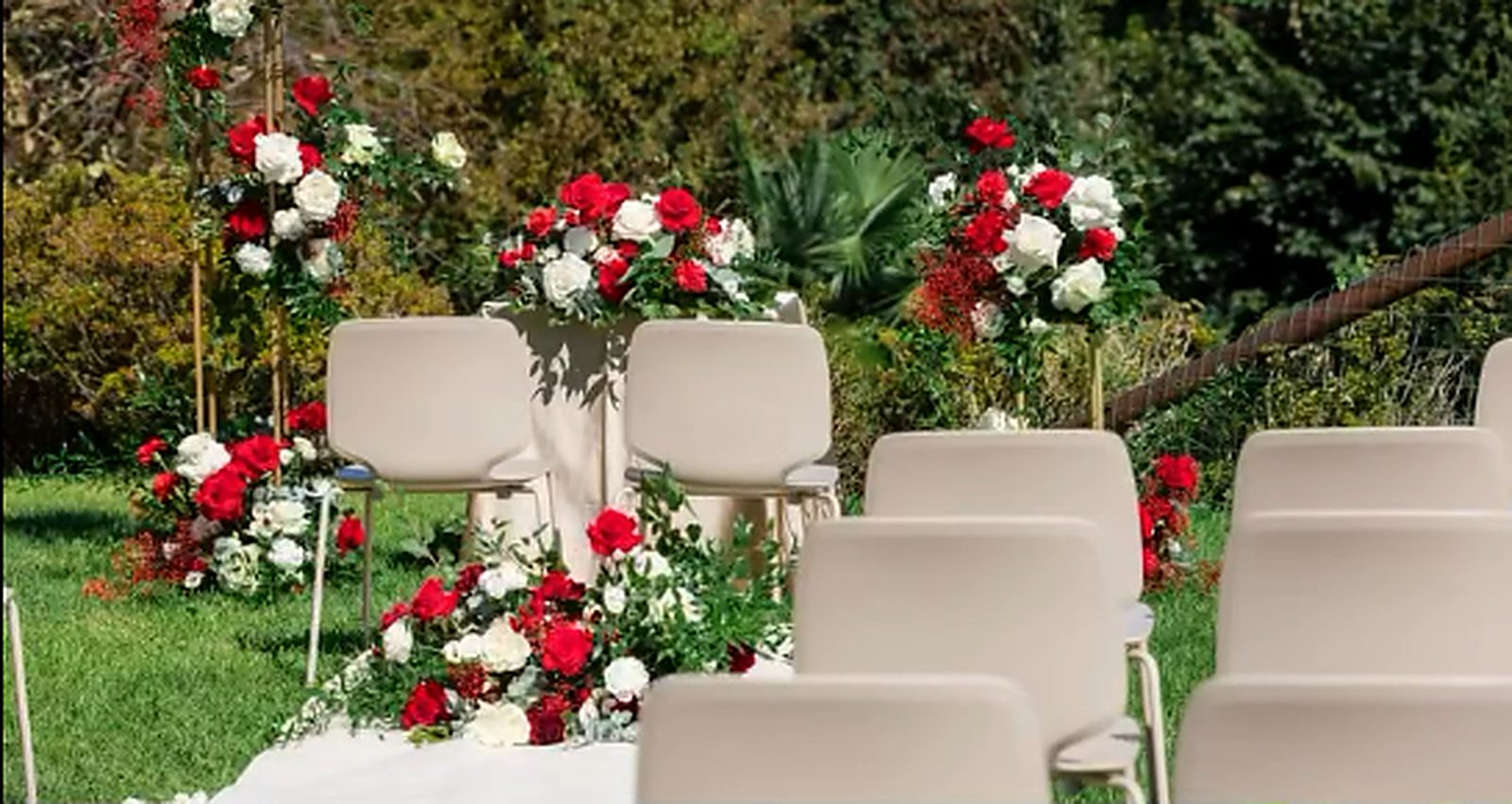 Le sedie e le composizioni di rose rosse pronte per la cerimonia sul prato Le sedie e le composizioni di rose rosse pronte per la cerimonia sul prato