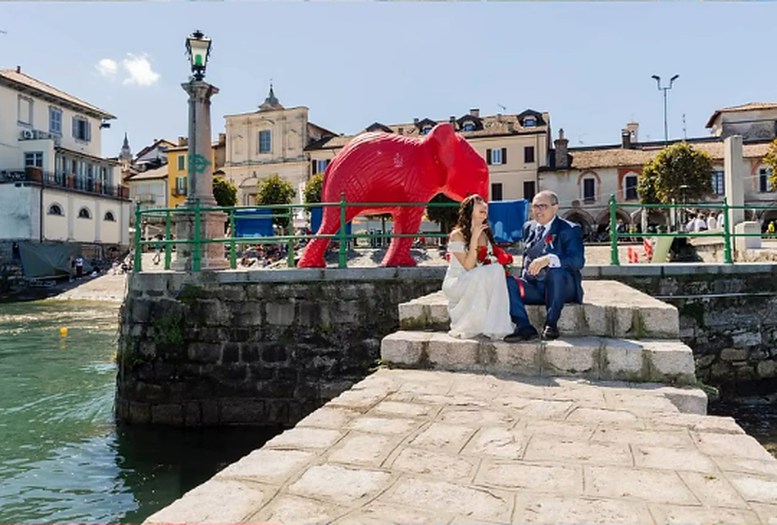Gli sposi seduti sul molo di Arona, sotto la scultura dell'elefante rosso Gli sposi seduti sul molo di Arona, sotto la scultura dell'elefante rosso
