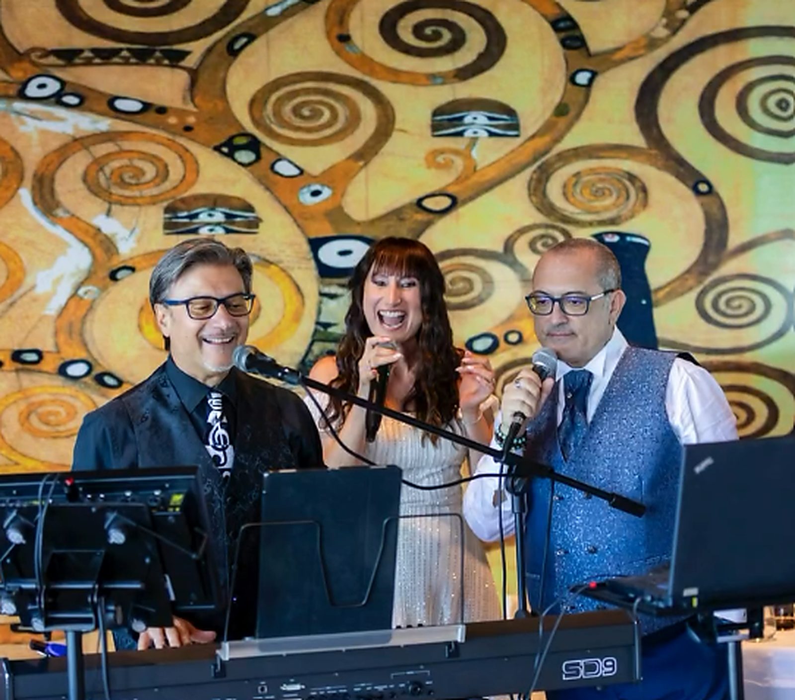 La sposa canta con i musicisti, davanti al grande murale dorato La sposa canta con i musicisti, davanti al grande murale dorato