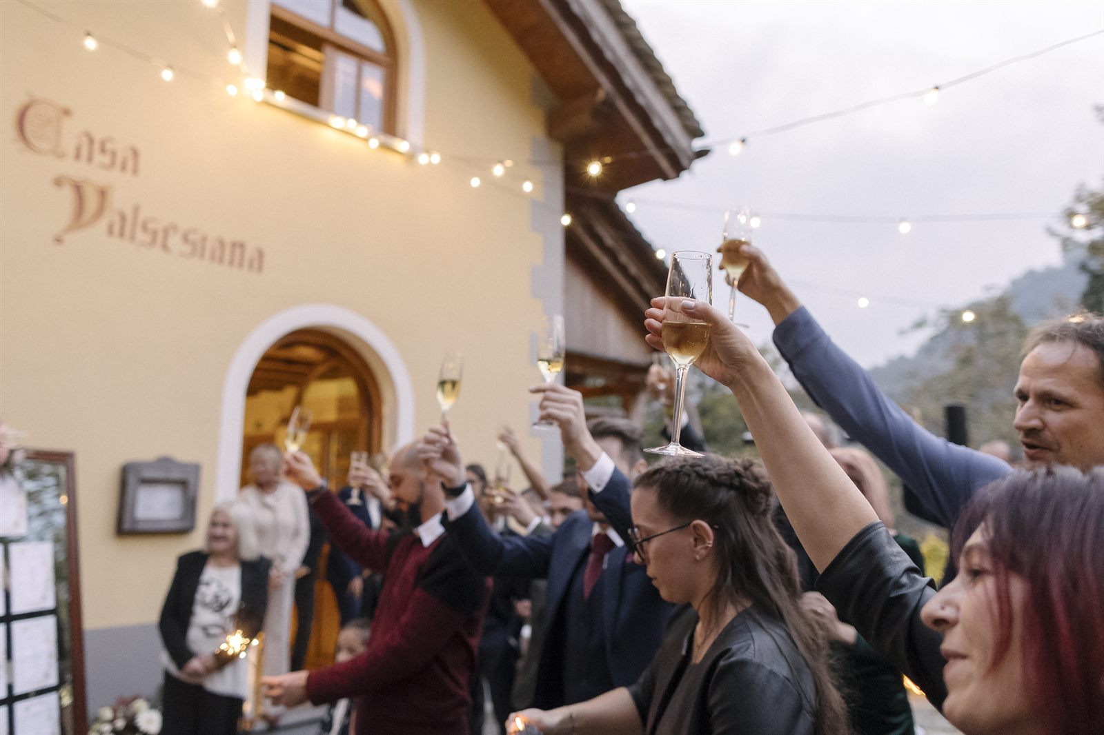 Gli invitati brindano fuori dal ricevimento con le luci della sera Gli invitati brindano fuori dal ricevimento con le luci della sera