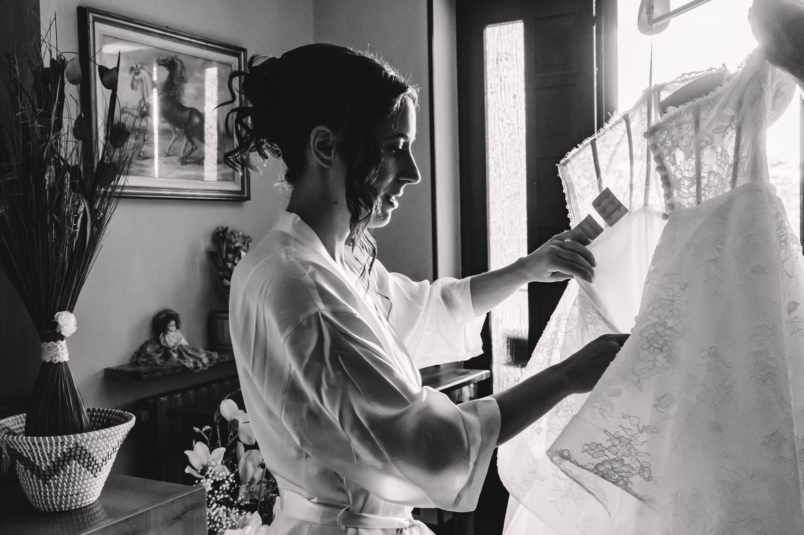 La sposa accanto all'abito appeso, bianco e nero La sposa accanto all'abito appeso, bianco e nero