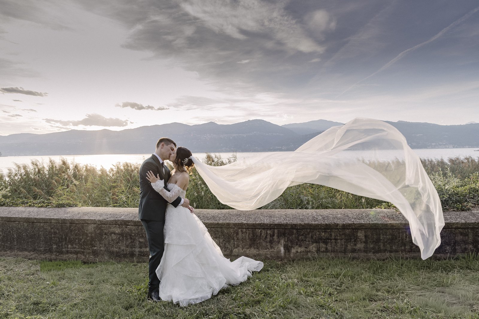 Il velo al vento durante il bacio in riva al lago