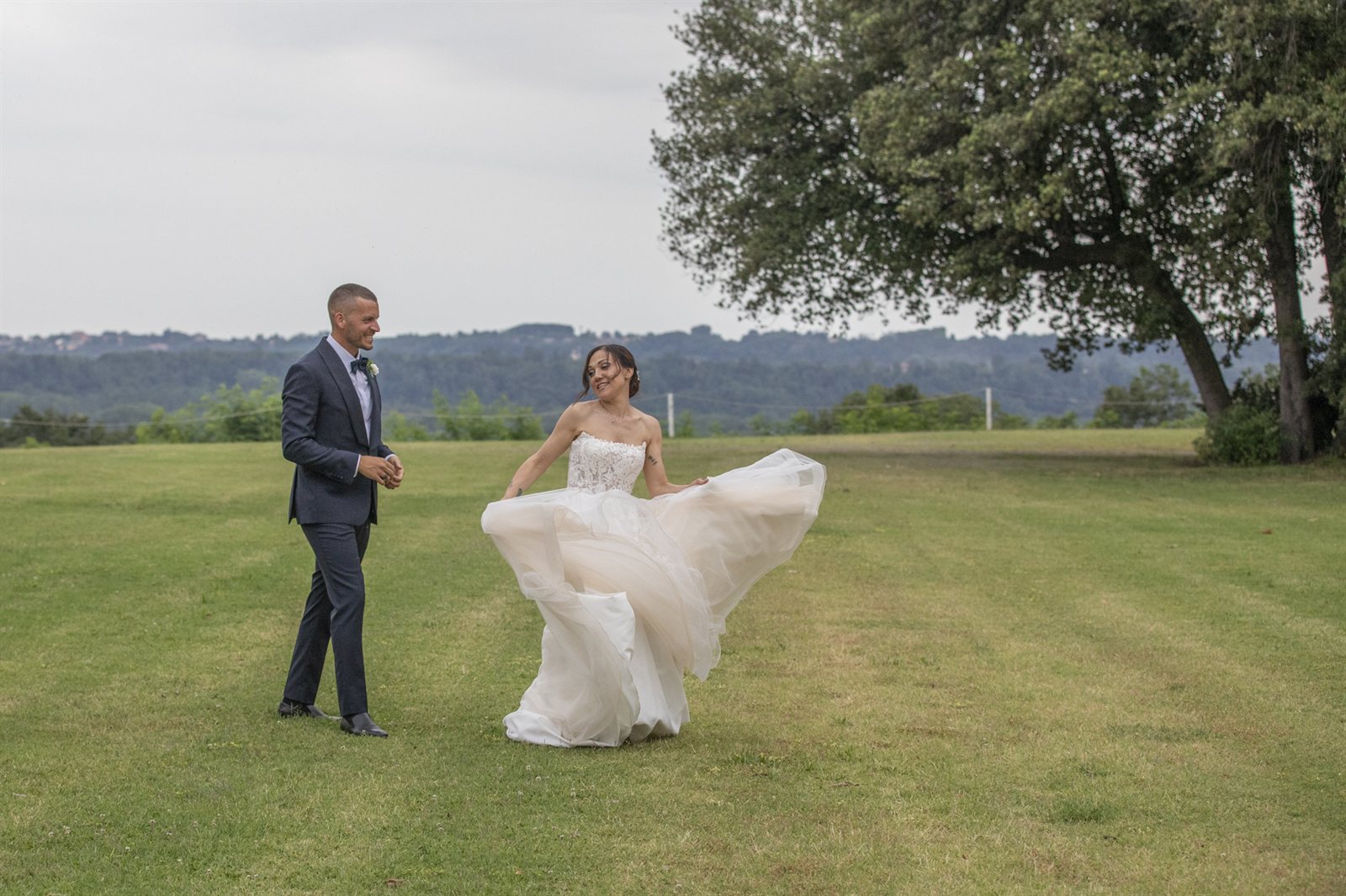 Gli sposi sul prato del parco, la sposa fa girare l'abito