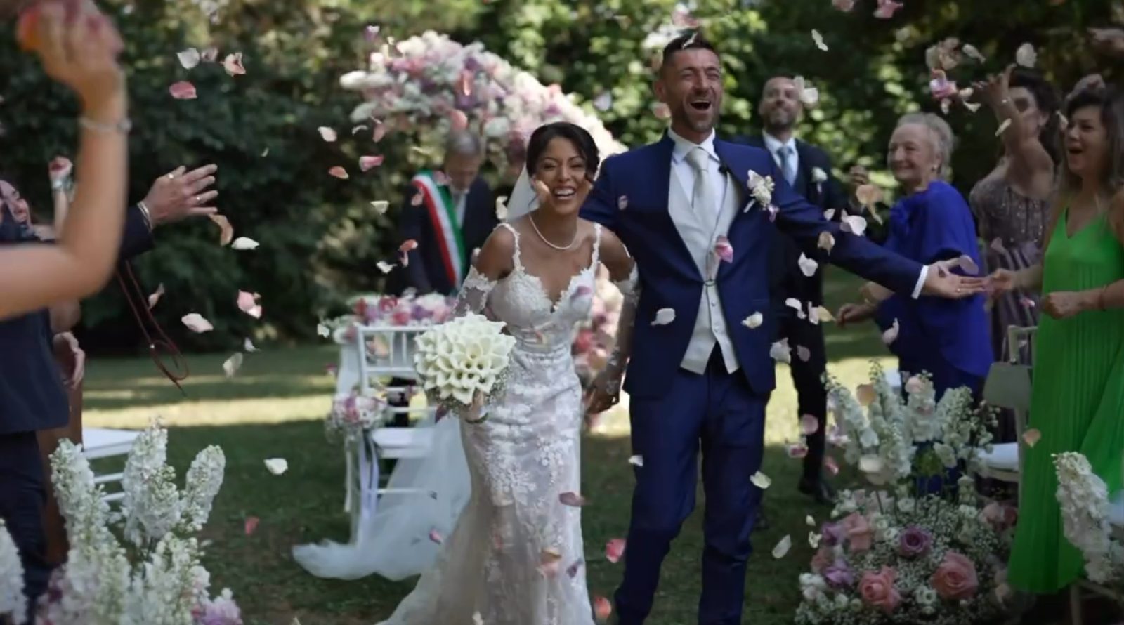 The couple walking out under a shower of petals