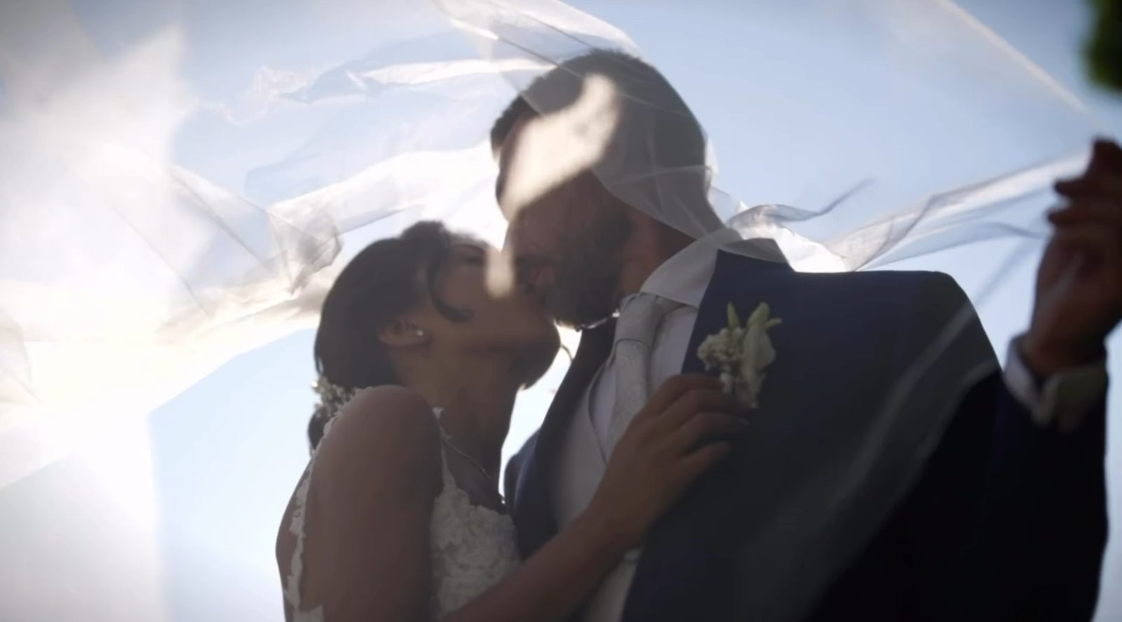 Il bacio sotto il velo controluce, con il cielo aperto