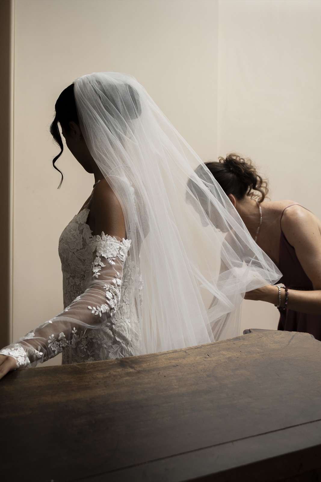 La sposa al tavolo con il velo, mentre la aiutano La sposa al tavolo con il velo, mentre la aiutano