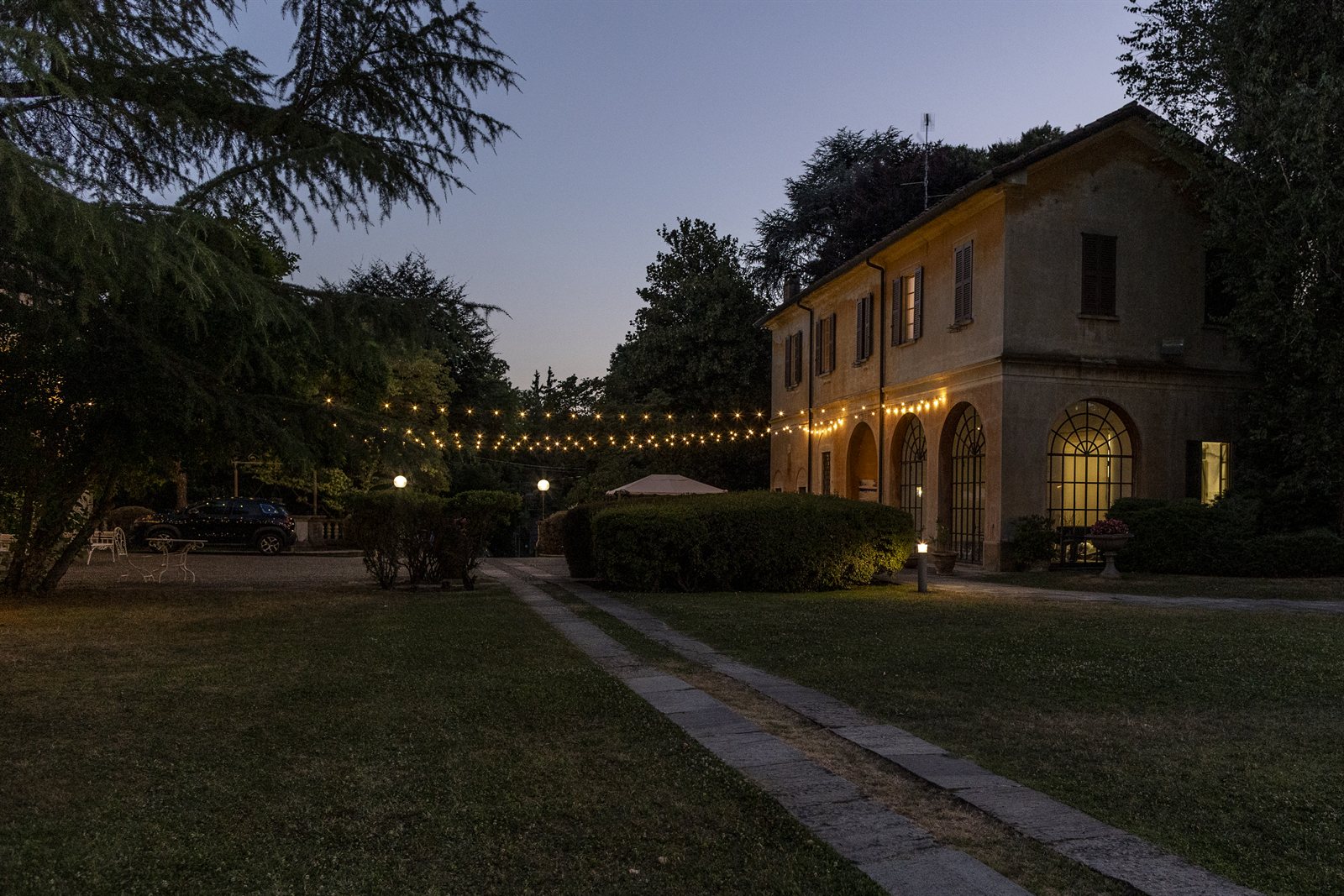 La villa e il vialetto all'imbrunire, con le luci accese La villa e il vialetto all'imbrunire, con le luci accese