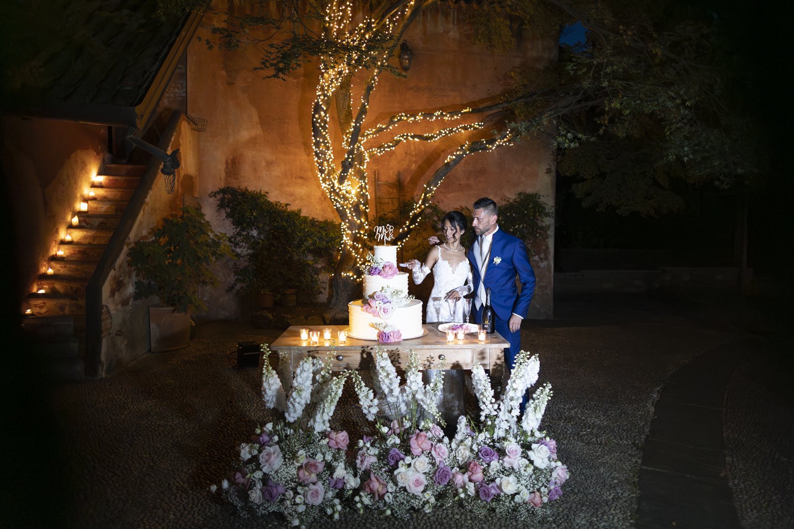 Il brindisi davanti alla torta, la villa illuminata di sera